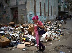 dpatopbilder 19 03 2026 kuba havanna eine frau geht auf einer strasse vorbei an muellbergen