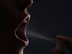 geoeffneter mund einer jungen frau in den sie mundspray sprueht open mouth of a woman who is applying mouth spray
