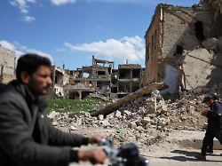 anwohner gehen an den ruinen von gebaeuden vorbei die waehrend des krieges im nordosten syriens zerstoert wurden