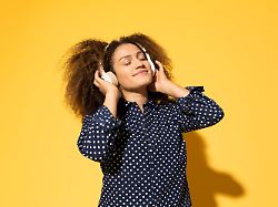 beautiful woman enjoying music against yellow background model released symbolfoto mikf00604