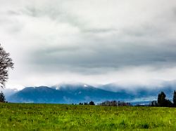 blick auf die wolkenverhangenen berge in der naehe von riedering in bayern