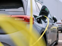 ein elektrofahrzeug von volkswagen laedt mit einem gelben kabel an einer ladesaeule