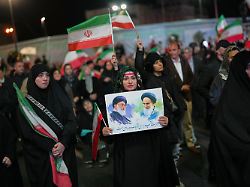 eine frau haelt ein plakat mit dem verstorbenen obersten fuehrer chamenei l und dem verstorbenen revolutionsgruender chomeini waehrend einer regierungsfreundlichen versammlung in teheran