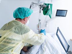 eine pflegekraft steht am krankenbett einer schwerkranken patientin im krankenhaus