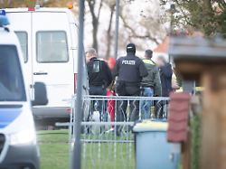 eine tatverdaechtige frau mitte l verlaesst in begleitung von polizeibeamten ihr wohnhaus