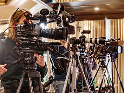fernseh und videokameras stehen vor dem podium einer pressekonferenz