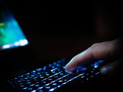 hand auf einer laptop tastatur in einem dunklen raum