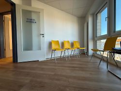 symb wartezimmer glastuer mit der aufschrift wartezimmer drei gelben stuehle stehen ohne patienten in einer artzt praxis allgemein zahnarzt maerz 2026