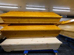 saerge mit verstorbenen stehen im krematorium uebereinander auf rollwagen in der kuehlhalle