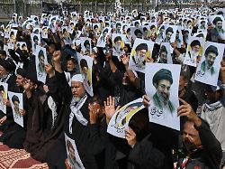 schiitische muslime halten plakate mit dem bild des modschtaba chamenei und seines verstorbenen vaters ajatollah ali chamenei um ihre unterstuetzung waehrend einer prozession in karachi zu zeigen