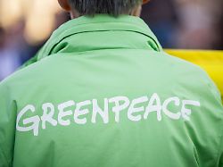 symbolbild zu greenpeace eine demonstrantin traegt eine jacke mit dem logo von greenpeace aufgenommen im rahmen einer demonstration zur energiewende vor dem kanzleramt in berlin 03 03 2026
