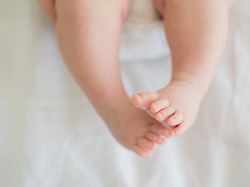 tiny newborn infant baby feet and toes on white background soft newborn baby foot legs under the white blanket close up of infant barefeet maternity tenderness parenthood birthday