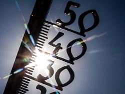 vor einem wolkenlosen blauen himmel zeigt ein aussenthermometer in einem garten bereits am vormittag ueber 30 grad lufttemperatur an