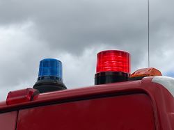 blaue und rote signalleuchten auf dem dach eines roten einsatzfahrzeugs unter bewoelktem himmel