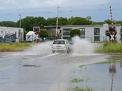 ein auto faehrt an einem bahnuebergang durch eine pfuetze nach der sommerhitze hat ein wetterumschwung am wochenende in teilen bayerns fuer zahlreiche witterungsbedingte einsaetze gesorgt