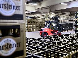 ein gabelstapler ist in der logistik der warsteiner brauerei zwischen bierkaesten unterwegs