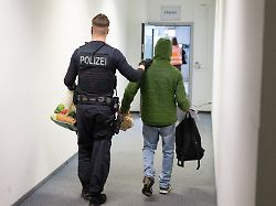 ein polizeibeamter bringt einen mann zu einem abschiebeflug nach pakistan