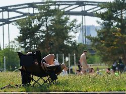 ein junger mann sitzt mit nacktem oberkoerper im hafenpark in der mainmetropole werden fruehsommerliche temperaturen von bis zu 30 grad erwartet