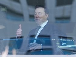 elon musk gestikuliert waehrend er durch einen flur im us bezirksgericht geht