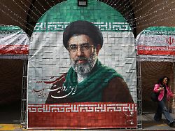 file photo a woman walks next to a banner with a picture of iran s new supreme leader mojtaba khamenei in tehran iran may 8 2026