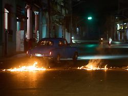 menschen fahren mit einem amerikanischen oldtimer durch eine barrikade die von anwohnern errichtet wurde die gegen anhaltende stromausfaelle in havanna protestieren 1