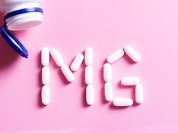 mineralstoffkapsel magnesium mg mineral pill capsule magnesium white vitamin pills forming shape to mg sign and plastic bottle on pink background copy space top view copyright xzoonar