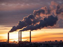 rauch aus der fabrik rohr der waermestation in der stadt in der winterzeit bei sonnenuntergang heizoel oder erdgaskraftwerk luftverschmutzung kamine oekologie heizsaison konzept