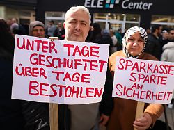 teilnehmer einer demonstration halten schilder in den haenden sie demonstrieren gegen das verhalten der sparkasse