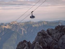 tiroler zugspitzbahn im sonnenaufgang ueber markanten felsen wolken und berggipfel im hintergrund