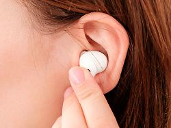 woman inserts wireless headphone in the ear