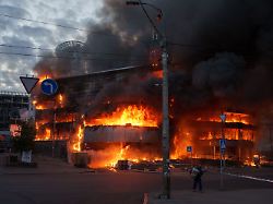 dpatopbilder 24 05 2026 ukraine kiew ein mann traegt eine kiste aus einem brennenden handelszentrum nach einem russischen angriff auf kiew