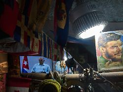 an image of cuban revolutionary hero ernesto che guevara stands next to a tv showing cuban president miguel diaz canel speaking inside a souvenir shop in havana cuba friday march 13 2026