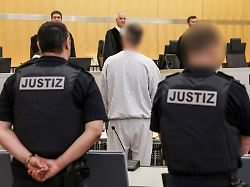 der angeklagte m steht zwischen justizangestellten im gerichtssaal der 50 jaehrige mann aus der rechten szene in dortmund soll zu attentaten auf bekannte politiker aufgerufen haben