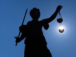 die silhouette der justitia statue auf dem roemerberg in frankfurt am main zeichnet sich gegen sonne ab dabei hat es den anschein als laege die sonne in ihrer gerechtigkeitswaage