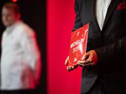 ein mitarbeiter haelt ein 1 sterne michelin schild in den haenden mit den guide michelin sternen werden jaehrlich die besten restaurants deutschlands ausgezeichnet