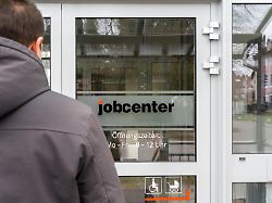 ein junger mann steht vor dem eingang eines jobcenters