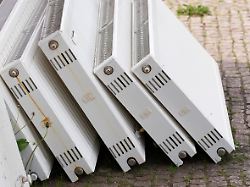 heizungstausch ausgebaute heizkoerper stehen an einem wohnhaus
