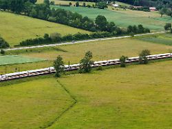 highspeed auf schienen alltagsverkehr auf asphalt ein ice der deutschen bahn ueberholt autos an der bundesstrasse bei seiner fahrt durch gruene wiesen naehe fulda 04 06 2026