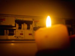 kerzenlicht vor einem sicherungskasten konzept blackout strom stromausfall candlelight before a fuse box concept blackout electricity power failure 1028901739
