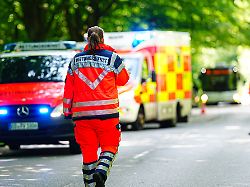 sanitaeterin geht in uniform an einer unfallstelle zum rettungswagen auf der uniform steht rettungsdienst symbolfoto blaulicht 16 06