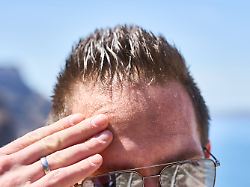 santorini greece may 8 2024 sweating man on a summer day wipes the beads of sweat from his forehead schwitzender mann an einem sommertag wischt sich die schweissperlen von der stirn