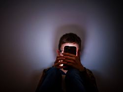 symbolfoto gestellte aufnahme zum thema kinder nutzen social media ein junge sitzt in einem dunklen raum und wird von einem smartphone beleuchtet berlin 16 02 2026