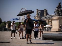 touristen mit regenschirmen spazieren waehrend einer hitzewelle durch paris