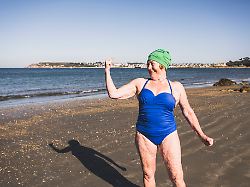 woman showing biceps at beach on sunny day model released symbolfoto uuf27325