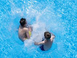 zwei jungen springen im freibad zacke vom beckenrand ins wasser aufgrund des schoenen fruehlingswetters startet das erlebnisbad ab sofort in die badesaison