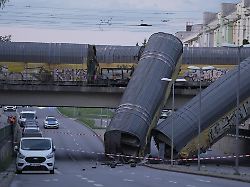zwei waggons eines gueterzugs liegen auf einer strasse nachdem sie von einer bruecke gestuerzt sind