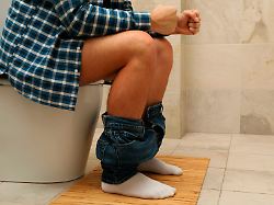 a man sits with his pants down on the toilet