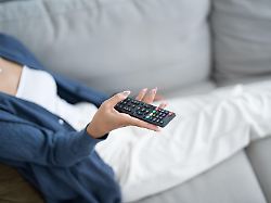 asian woman watching smart tv and using remote controller hand holding television audio remote control at home with the remote control television