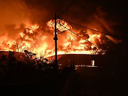bei einem waldbrand am rande der nordgriechischen stadt thessaloniki steigen flammen aus einem brennenden gebaeude auf