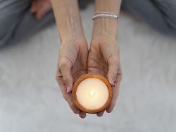 blick von oben auf eine brennende kerze die von einer meditativen frau gehalten wird modellfreigabe vorhanden
